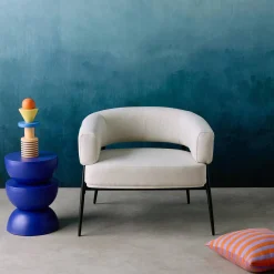 Sillón de tela con respaldo curvo y patas de metal