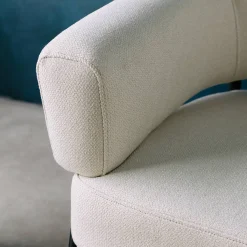 Sillón de tela con respaldo curvo y patas de metal