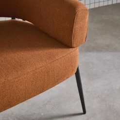 Sillón de tela con respaldo curvo y patas de metal