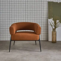 Sillón de tela con respaldo curvo y patas de metal