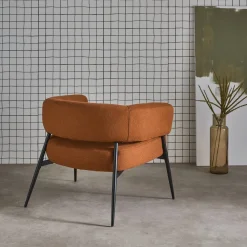 Sillón de tela con respaldo curvo y patas de metal