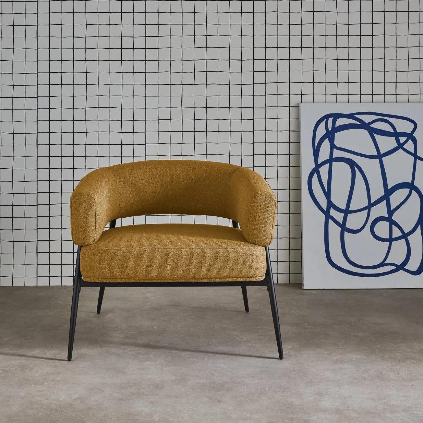 Sillón de tela con respaldo curvo y patas de metal