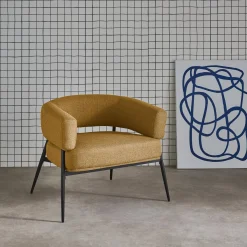 Sillón de tela con respaldo curvo y patas de metal