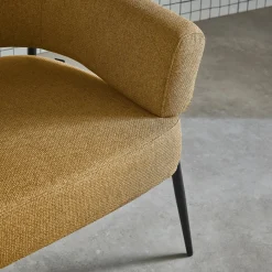 Sillón de tela con respaldo curvo y patas de metal