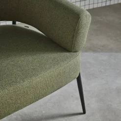 Sillón de tela con respaldo curvo y patas de metal